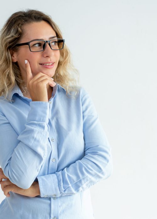 Content office employee studying information alongside of her. Beautiful Caucasian girl in eyeglasses leaning chin on hand and looking away. Advertising concept